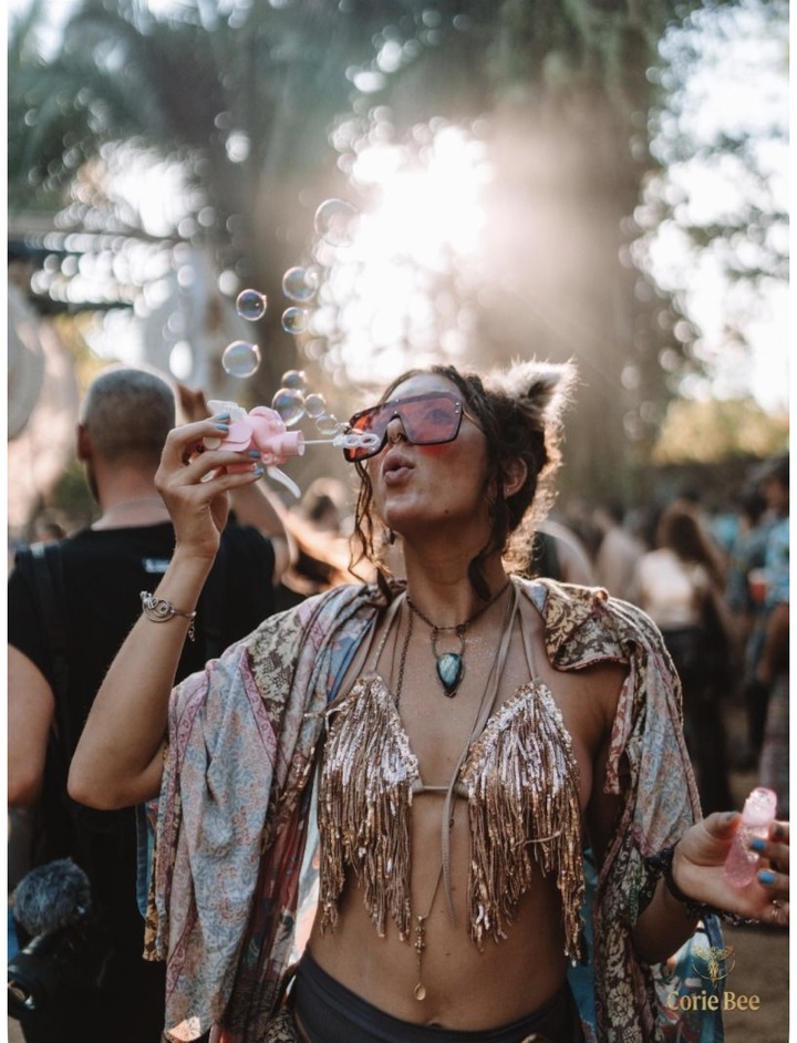 Mujer en un festival con top de flecos y kimono paisley haciendo burbujas